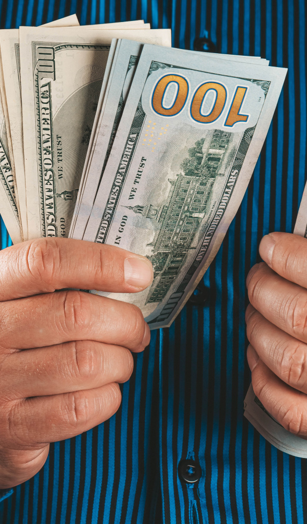 Мужчина считает сто долларовые купюры 