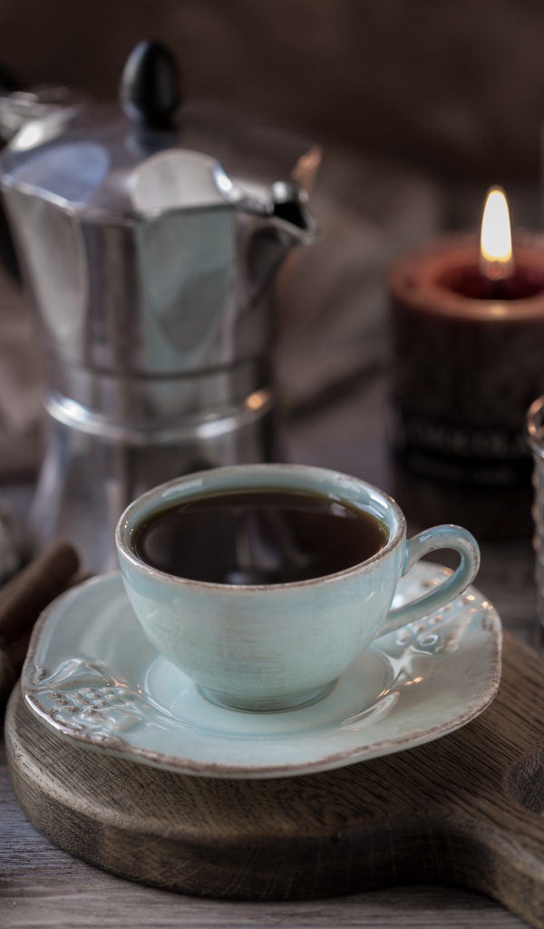 Чашка эспрессо на столе с корицей, зефиром и зажженными свечами