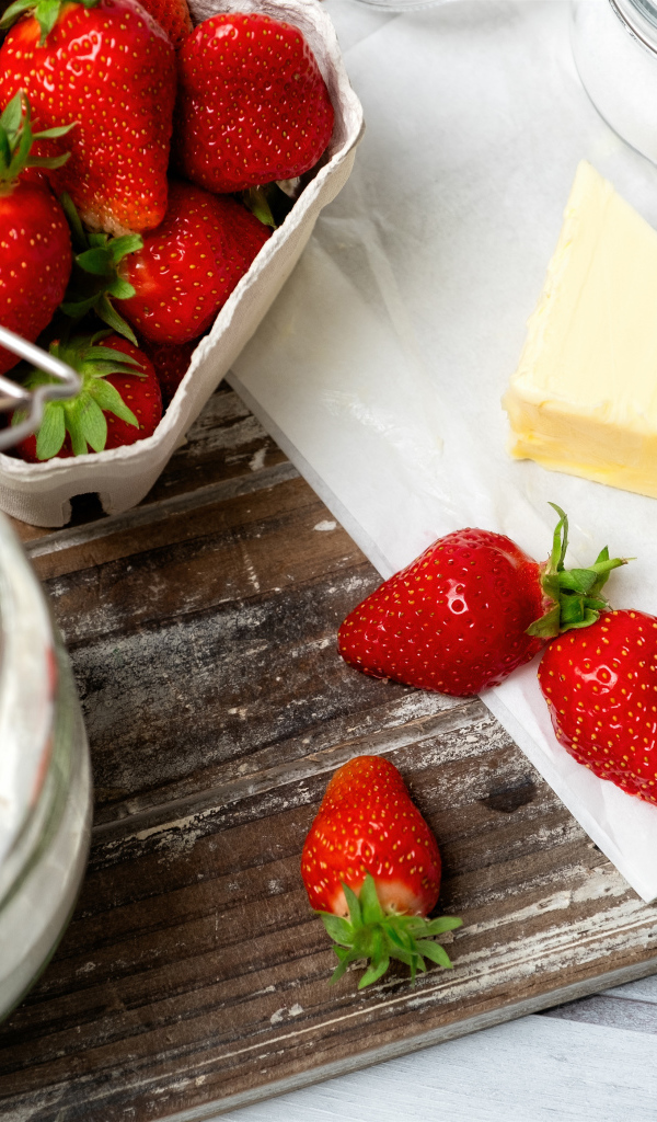 Кусок масла на столе с клубникой и мукой 