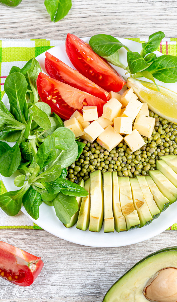 Аппетитные  свежие овощи с сыром и лимоном на тарелке 