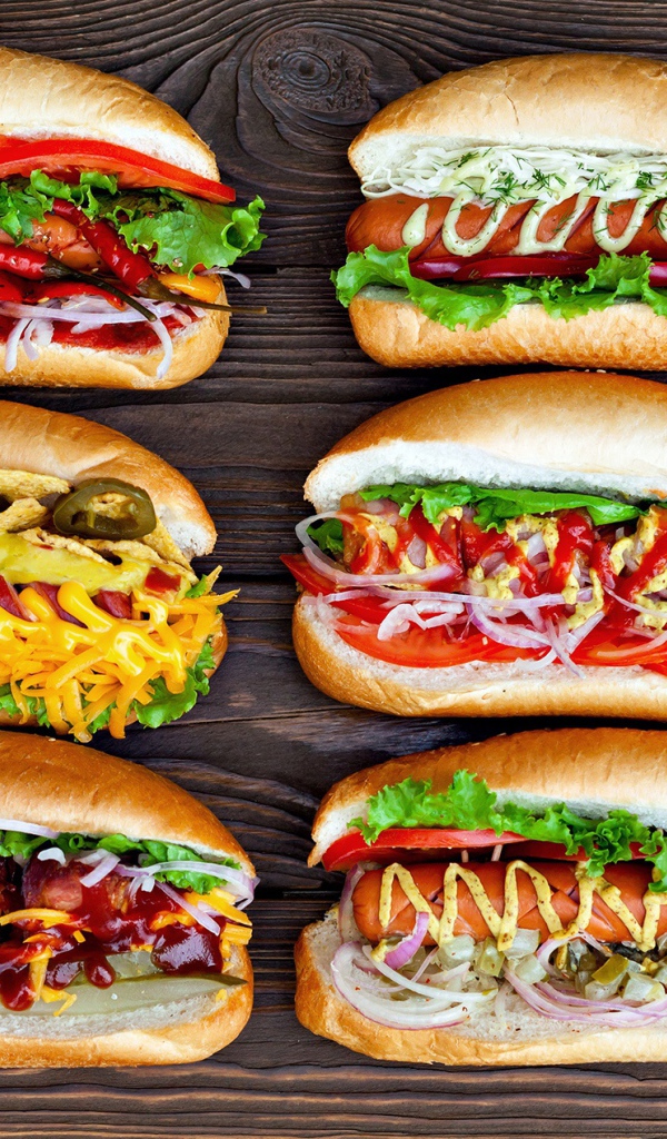 Аппетитные хот доги с разной начинкой на деревянном столе 