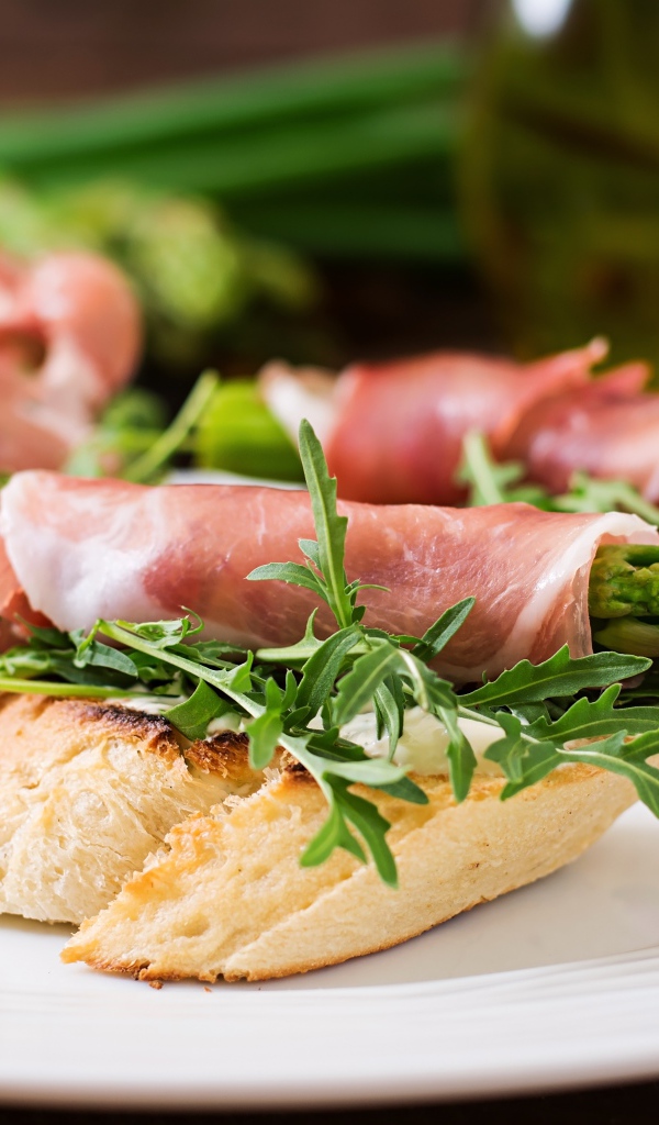 Рулетики с беконом и спаржей на тарелке с гренками