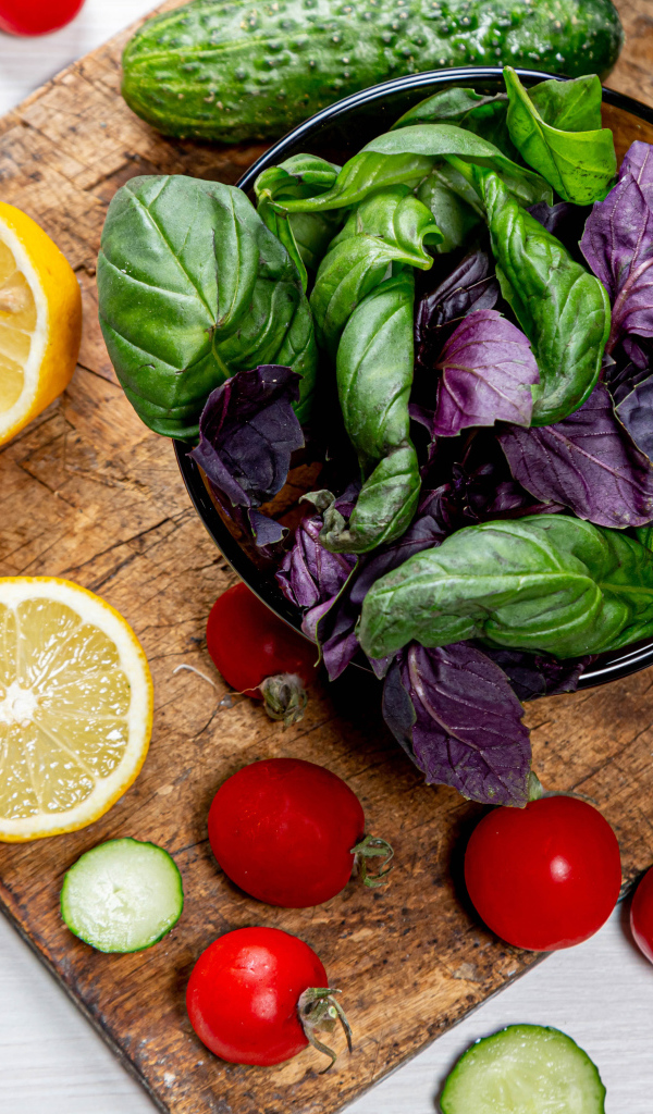 Базилик на столе с зеленью, помидорами и лимоном
