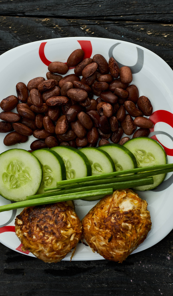 Фасоль на тарелке с оладьями и огурцами 