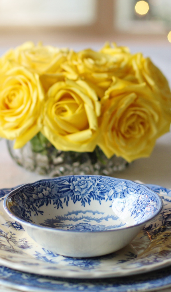 Красивая посуда на столе с букетом роз и свечами