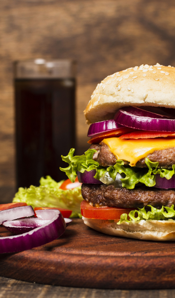 Большой гамбургер на столе с колой и картофелем фри 