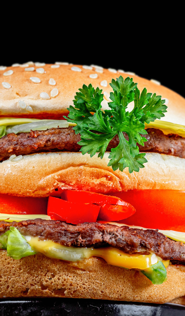 Большой гамбургер с котлетой на черном фоне