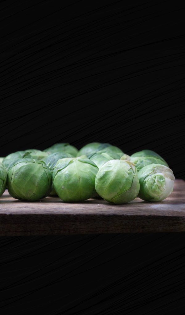 Брюссельская капуста на разделочной доске  на черном фоне