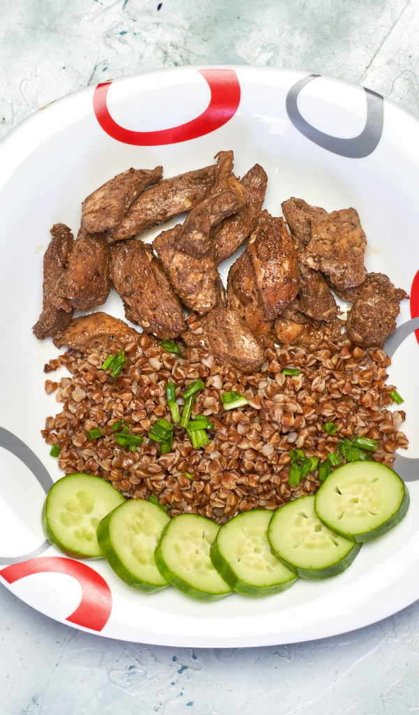 Гречка на тарелке с мясом и огурцами