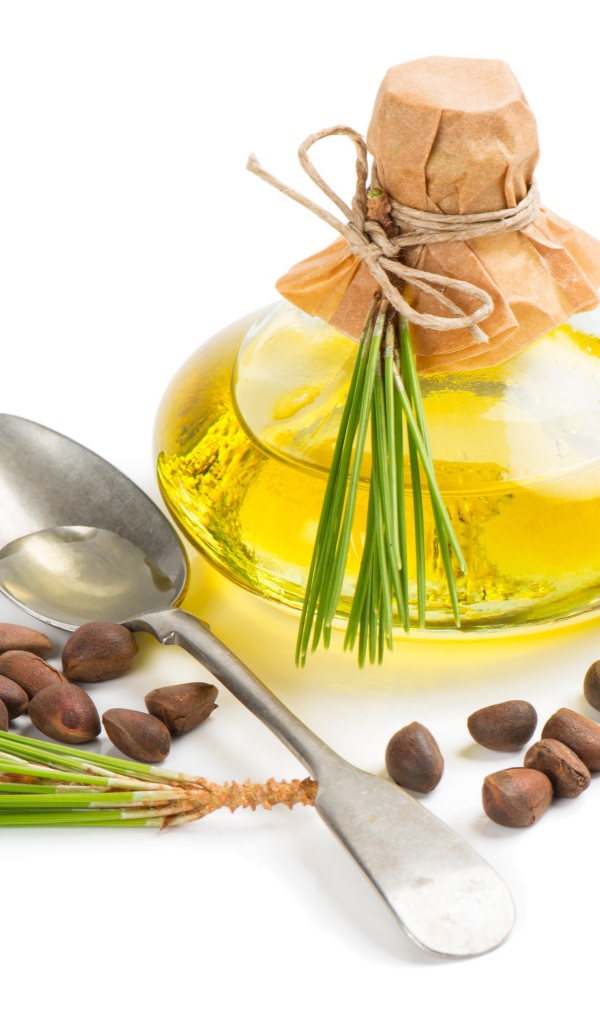 Кедровое масло на белом фоне с орехами и ложкой