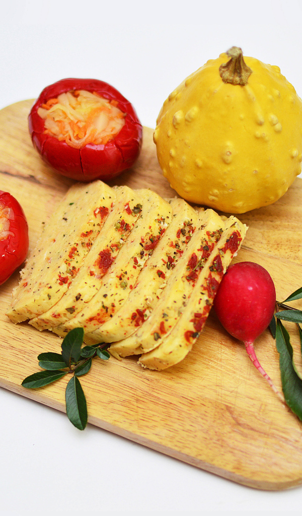 Сыр с овощами на разделочной доске на белом фоне