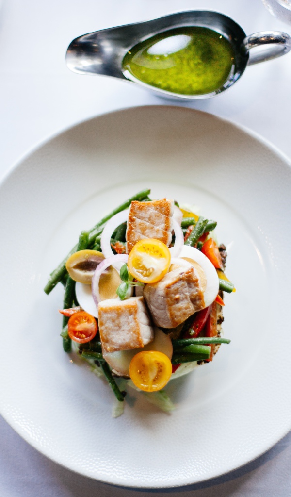 Салат из куриного филе с овощами на белой тарелке