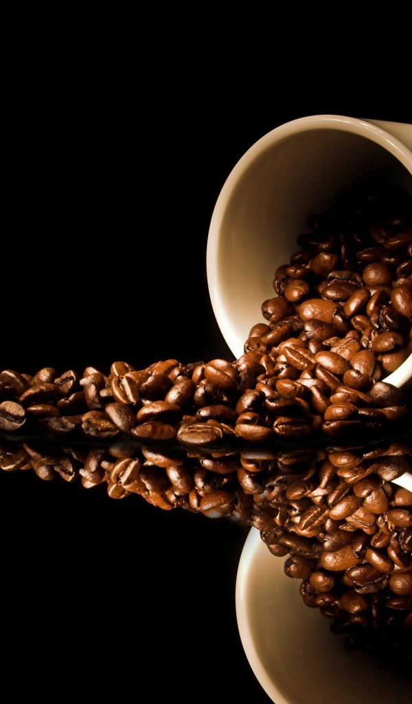 Кофейные зерна рассыпаны с белой кружки на стол