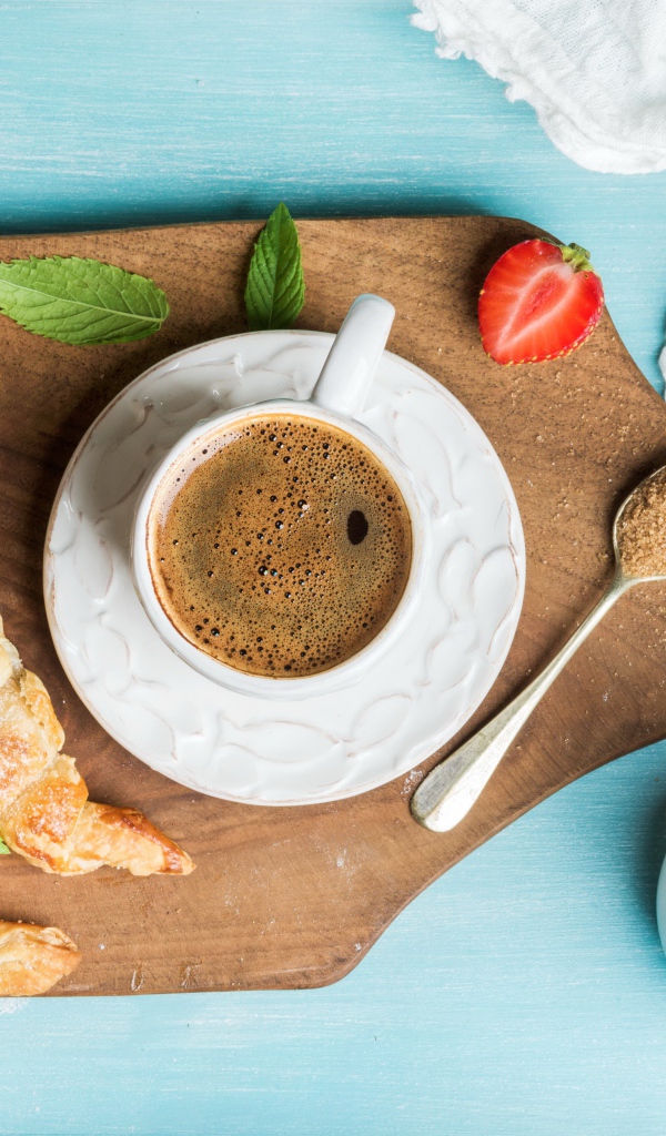 Чашка кофе на доске с клубникой и круассанами