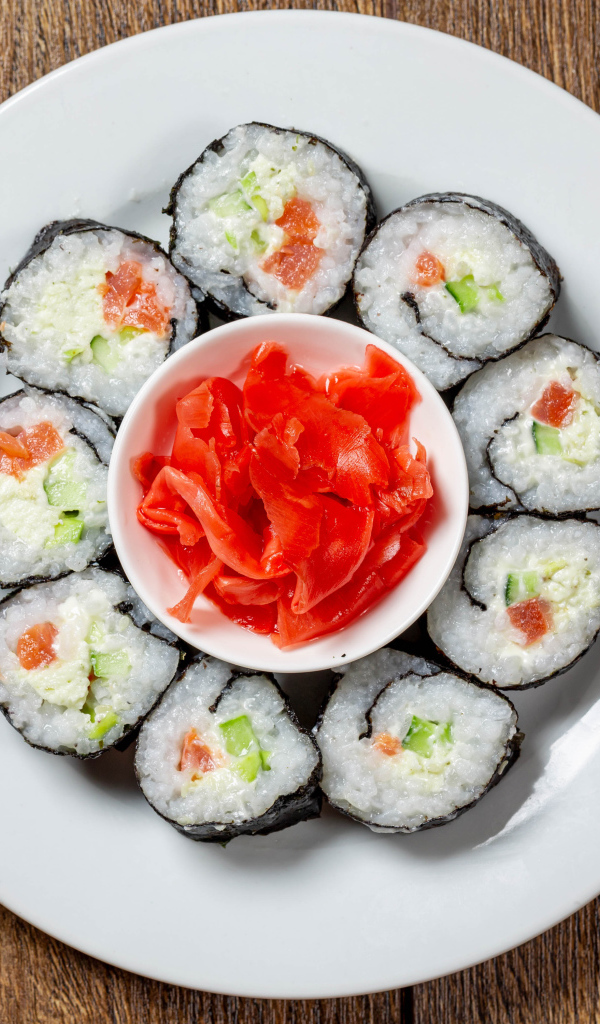 Вкусные суши на большой белой тарелке с имбирем