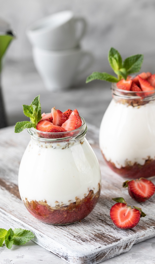 Десерт с йогуртом в банке с клубникой на столе цветами вишни 