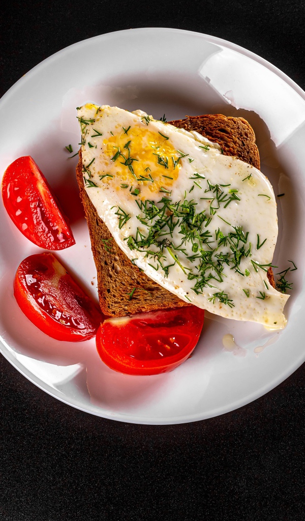 Бутерброд с яичницей на тарелке с помидорами