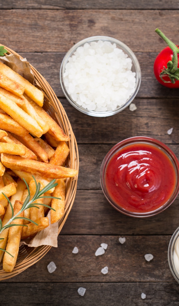 Картофель фри на столе соусом, солью и помидорами 