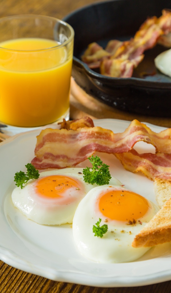 Яичница с беконом и тостами на столе с соком и кофе