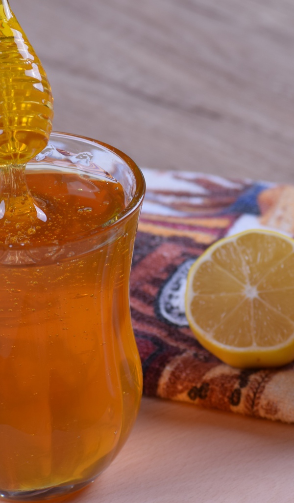 Стеклянная кружка с медом на столе с лимоном