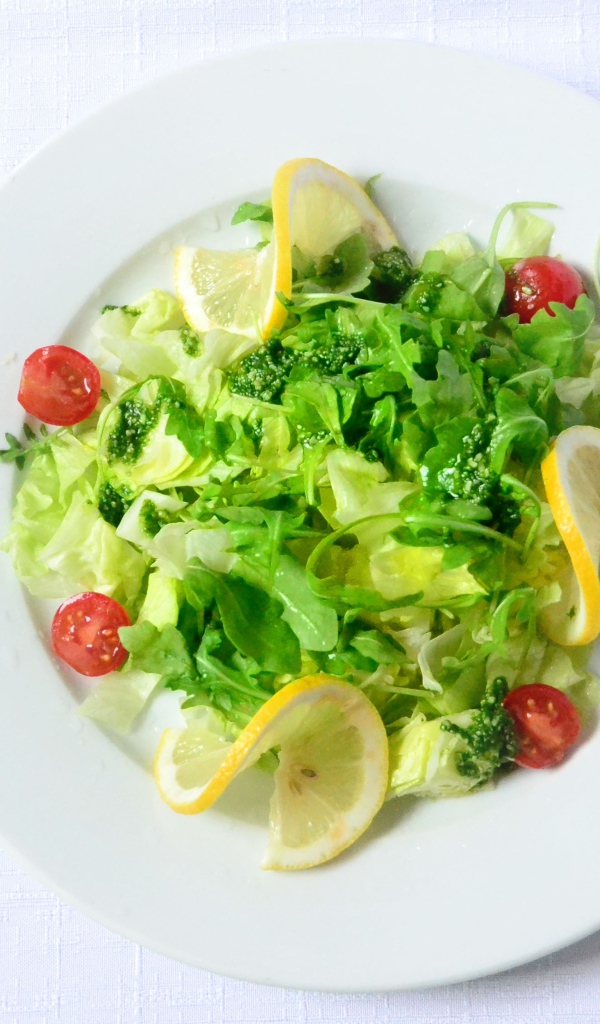 Салат из зелени с лимоном на белом фоне 