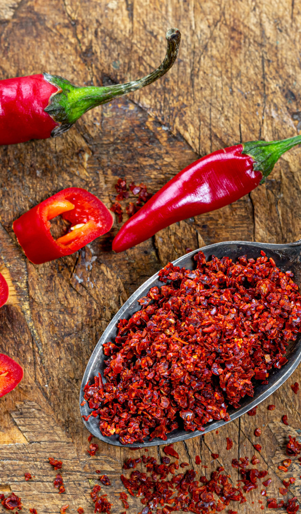 Молотый красный перец на ложке на столе 