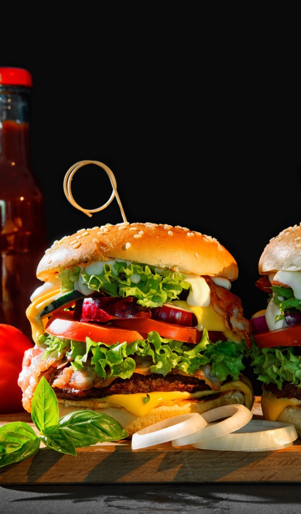 Гамбургеры на столе с картофелем и кетчупом на черном фоне