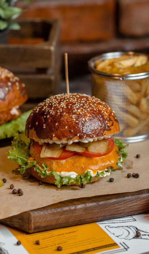 Гамбургеры на столе с помидорами, картофелем фри и солеными огурцами