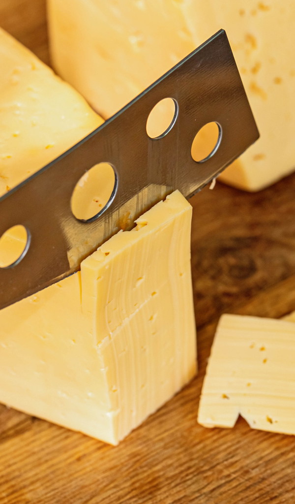 Твердый сыр с ножом на столе