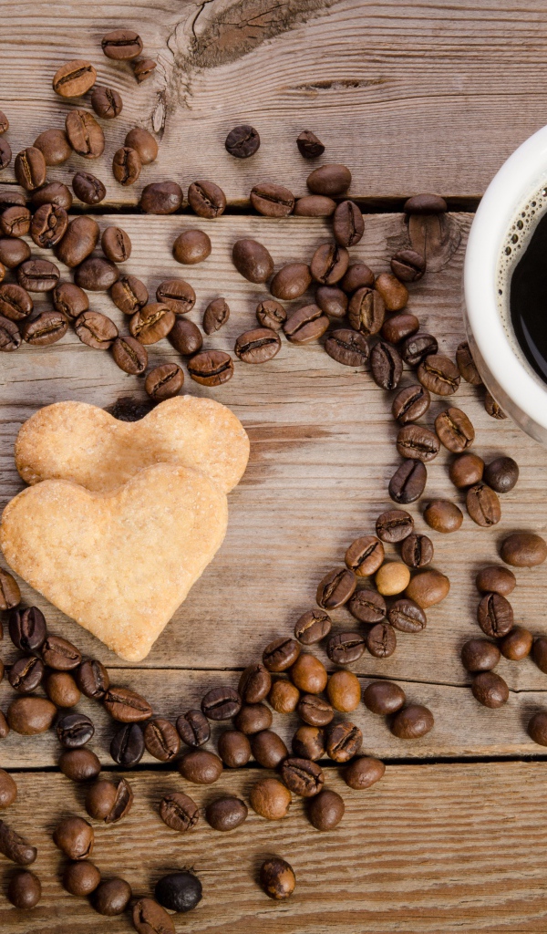 Печенье в форме сердца на столе с зернами и чашкой кофе 