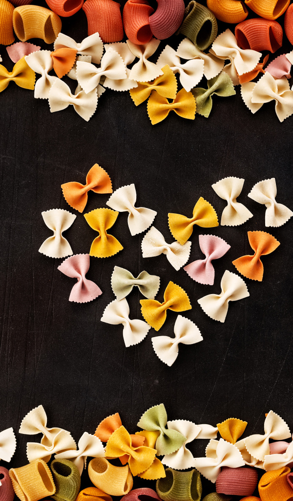 Сердце из разноцветных макарон на черном столе 