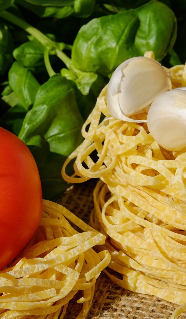 Домашняя лапша на столе с помидорами и базиликом