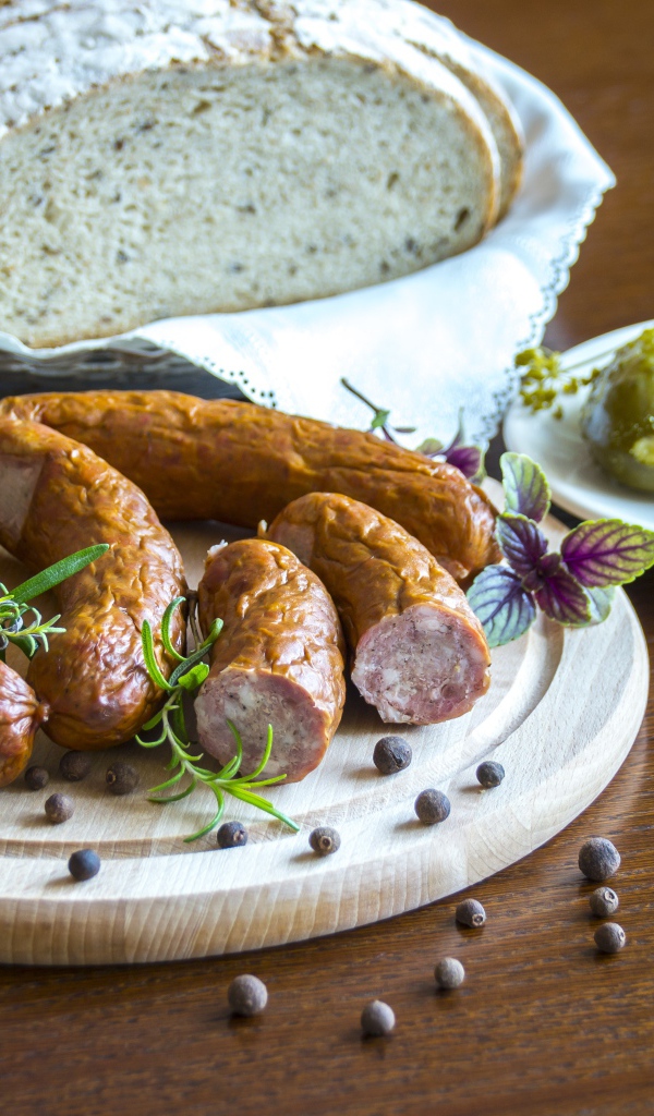 Домашняя колбаса на столе с хлебом и маринованными огурцами