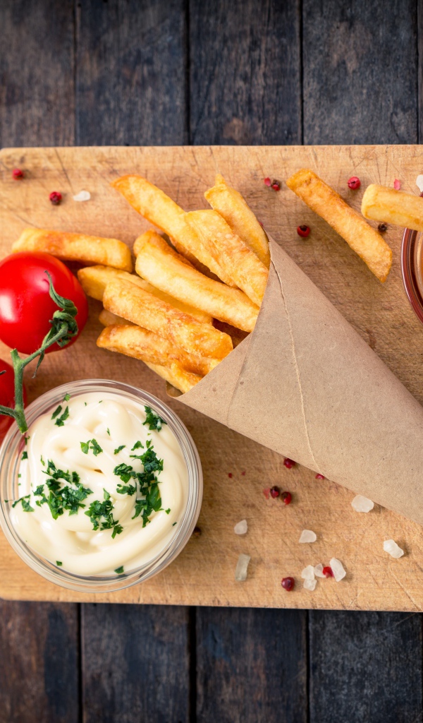 Кетчуп, соус и картофель фри на доске с помидорами