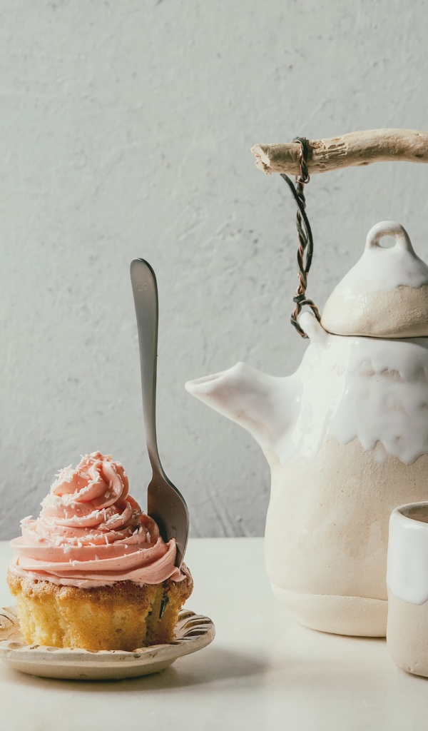 Чайник с чашкой на столе с кексом