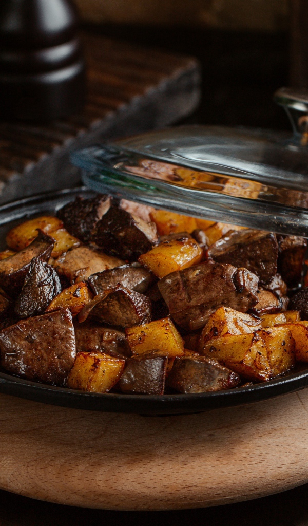 Печень с картофелем в сковороде на столе