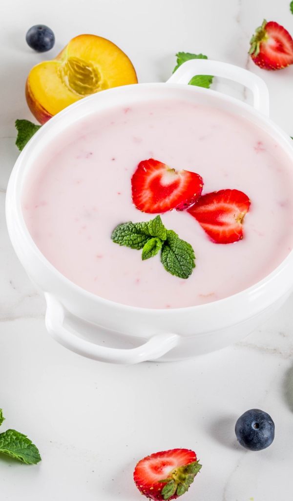 Молочный суп в тарелке на столе с ягодами и нектарином