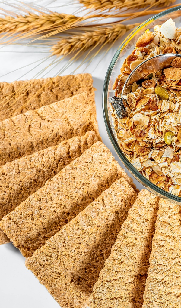 Мюсли в тарелке на столе с хлебцами 