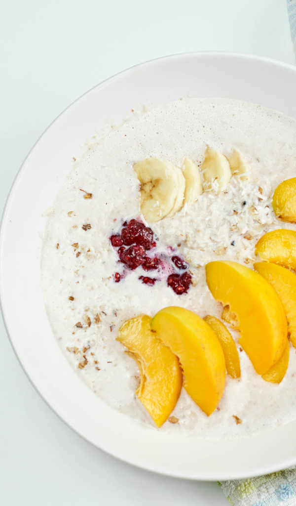 Мюсли с йогуртом в тарелке с кусочками банана и персика