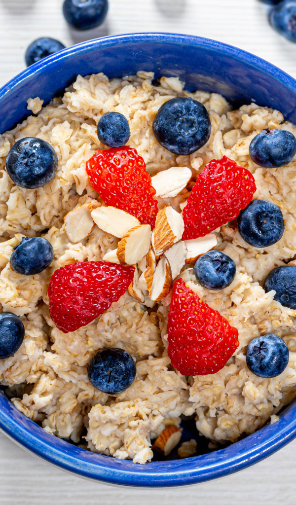 Овсяная каша в тарелке с ягодами черники и клубники 