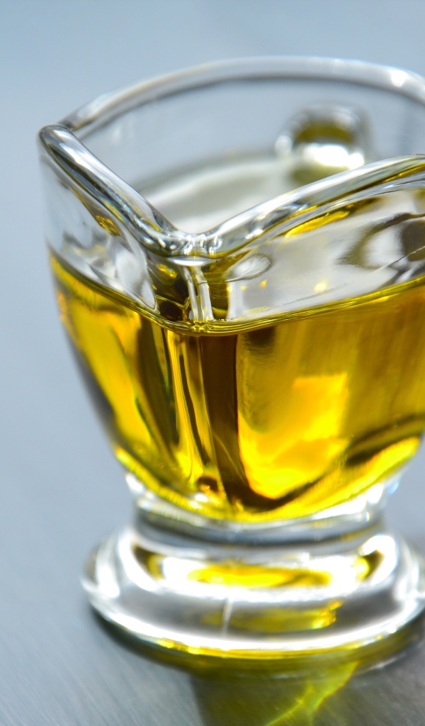 Оливковое масло в стеклянной вазе на столе 