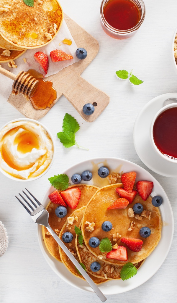 Оладьи с ягодами на столе с соком, чаем и мюсли на завтрак 