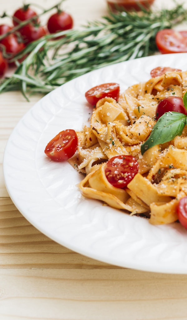 Паста с помидорами черри на белой тарелке