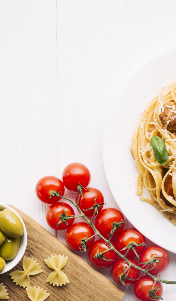 Паста с фрикадельками на столе с помидорами и оливками