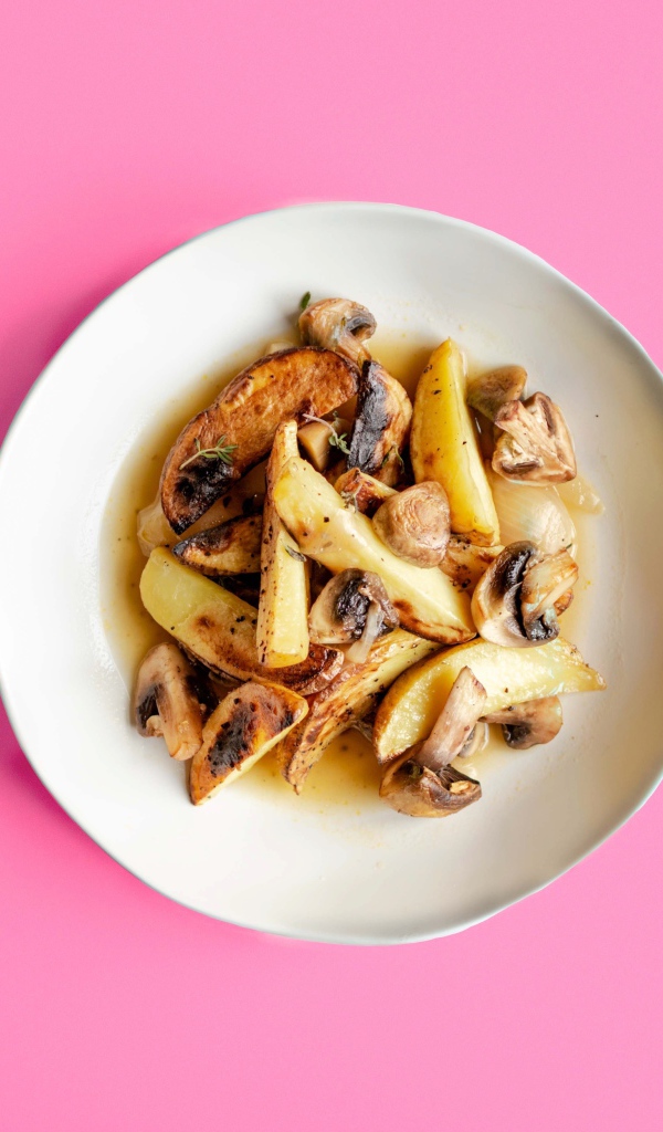 Картофель с грибами в тарелке на розовом фоне 