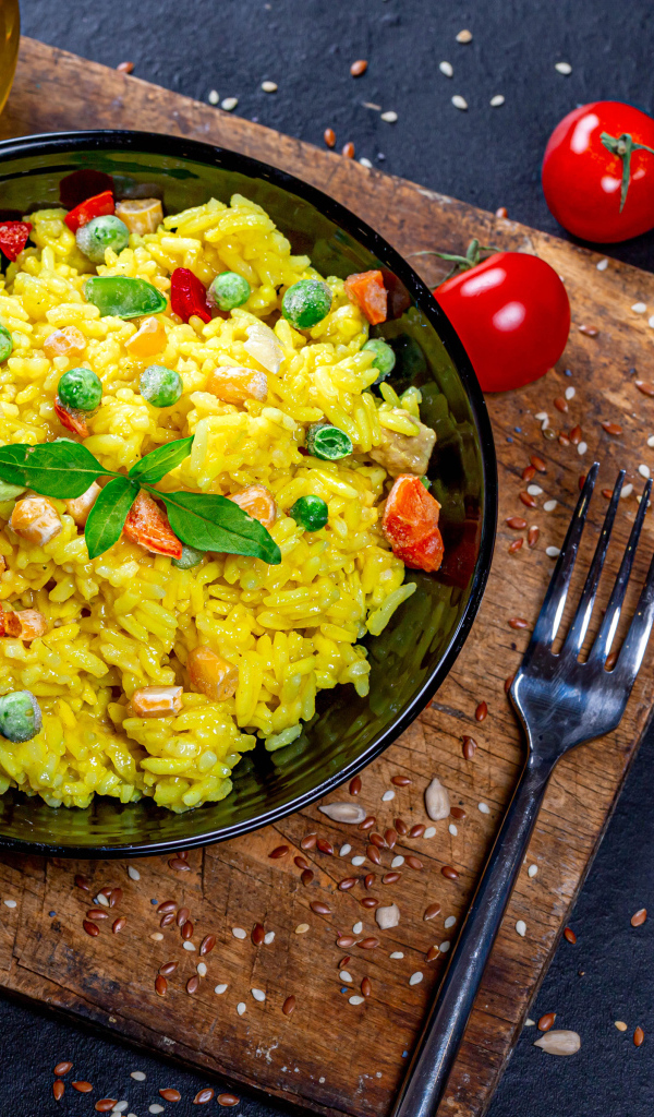 Рис с овощами на столе с маслом, зеленью и помидорами 