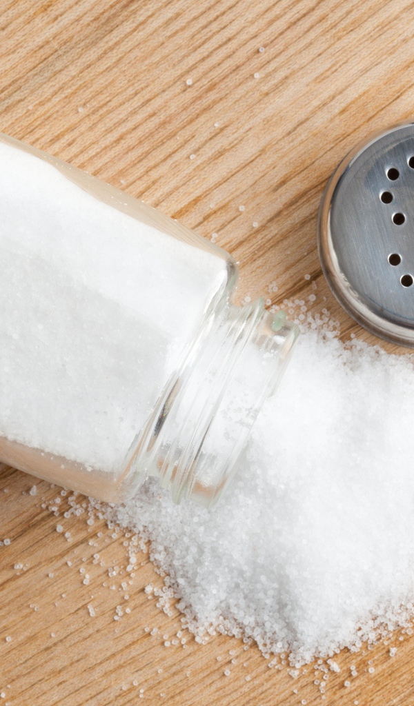 Соль рассыпана на деревянном столе 