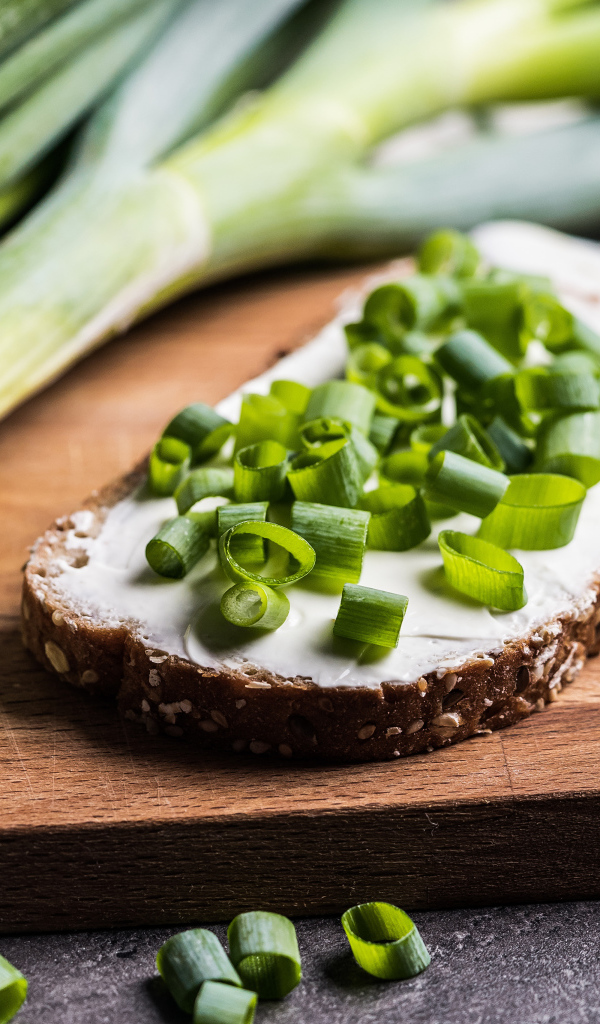Бутерброд с маслом и зеленым луком на столе 