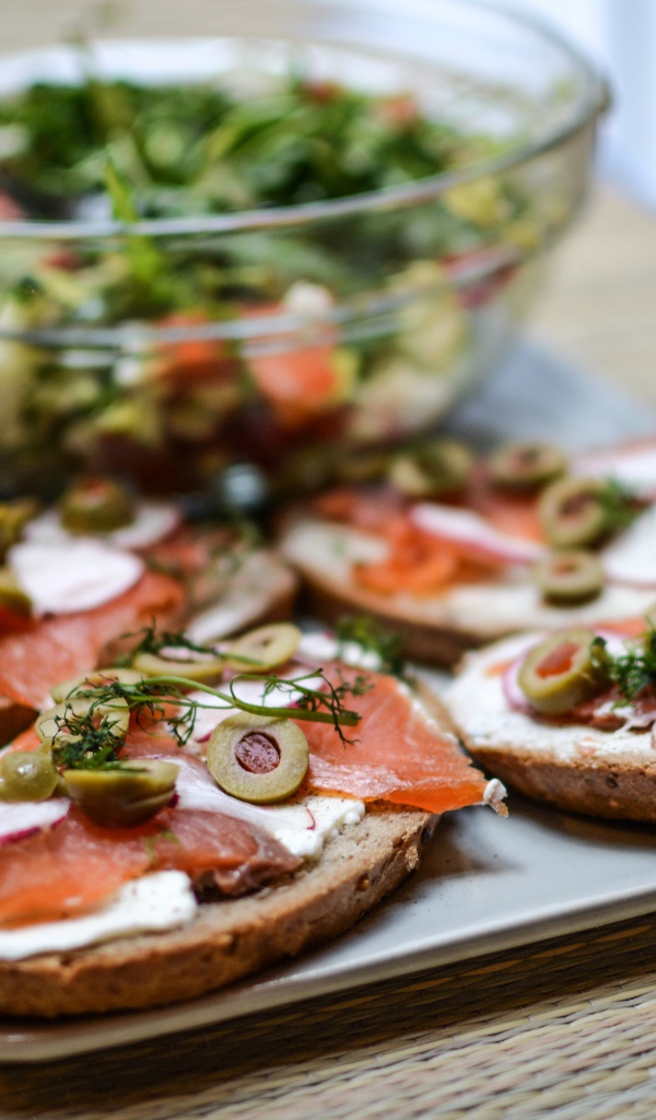 Бутерброды с маслом и красной рыбой на столе с салатом