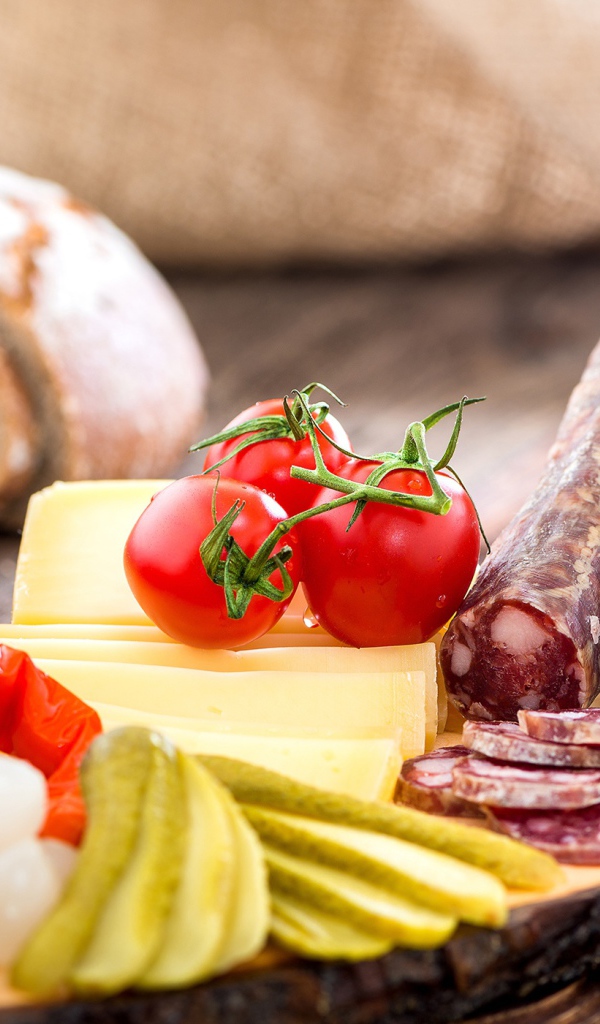 Колбаса на столе с огурцами, помидорами и перцем